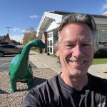 Capt. Russ beside a green dinosaur statue at Little America.